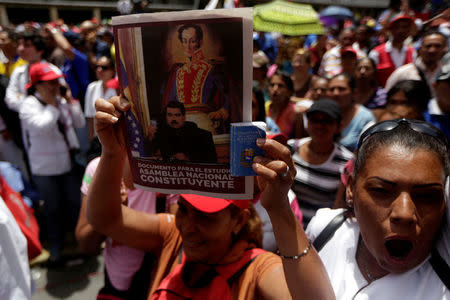 A government supporter holds up a flyer of Venezuela's President Nicolas Maduro during a rally in Caracas, Venezuela May 22, 2017. REUTERS/Marco Bello