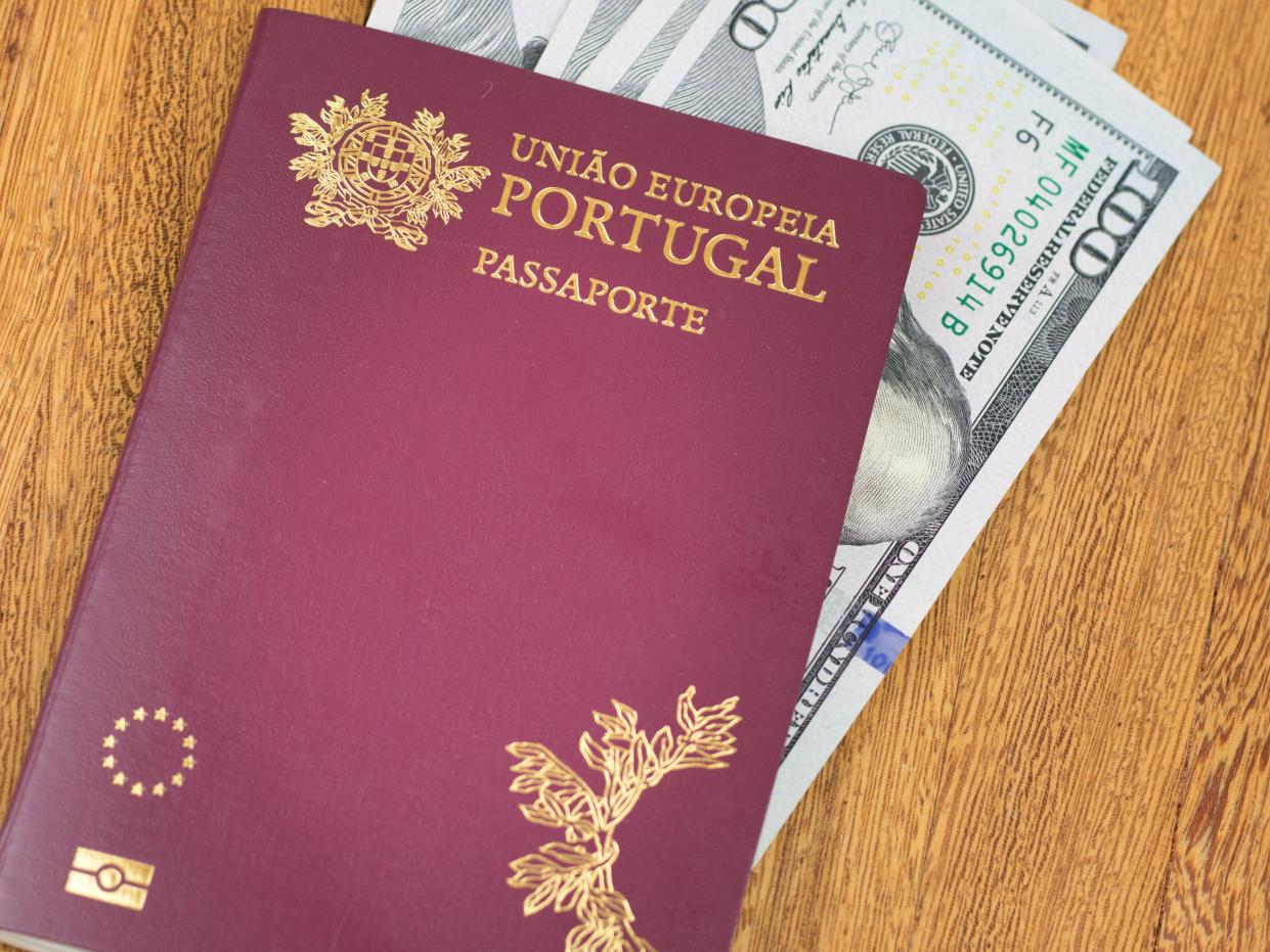 Portuguese passport (Translation "European Union Portugal passport") and one hundred dollar banknotes wooden background