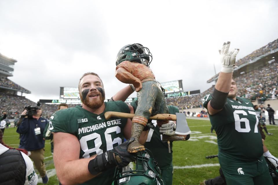 Michigan State defensive end Drew Beesley (86) carries the Paul Bunyan trophy to celebrate the 37-33 win over Michigan at Spartan Stadium in East Lansing on Saturday, Oct. 30, 2021. 