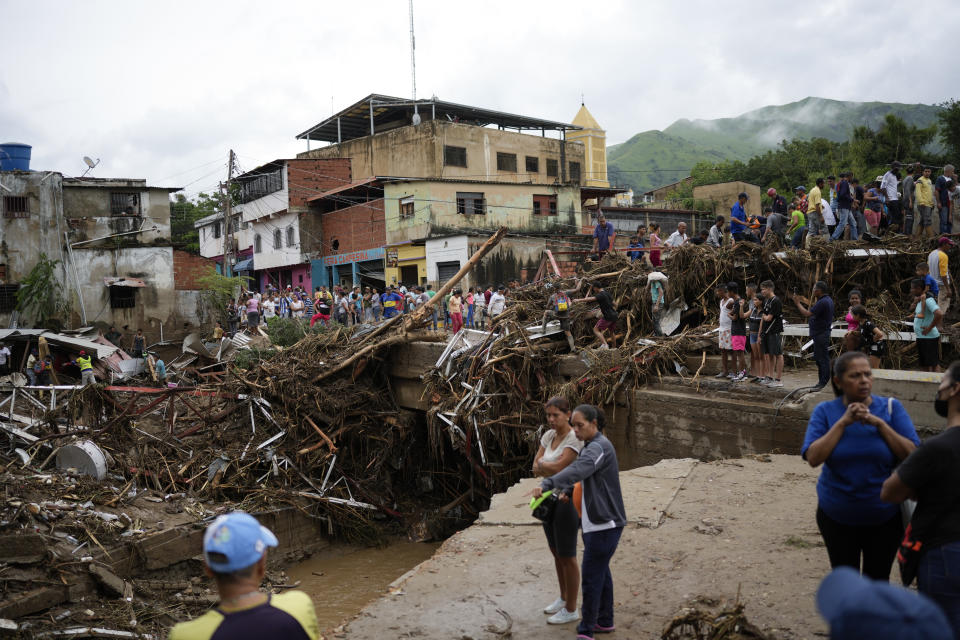 Residents look at damaged caused by flooding in Las Tejerias, Venezuela, Sunday, Oct. 9, 2022. (AP Photo/Matias Delacroix)