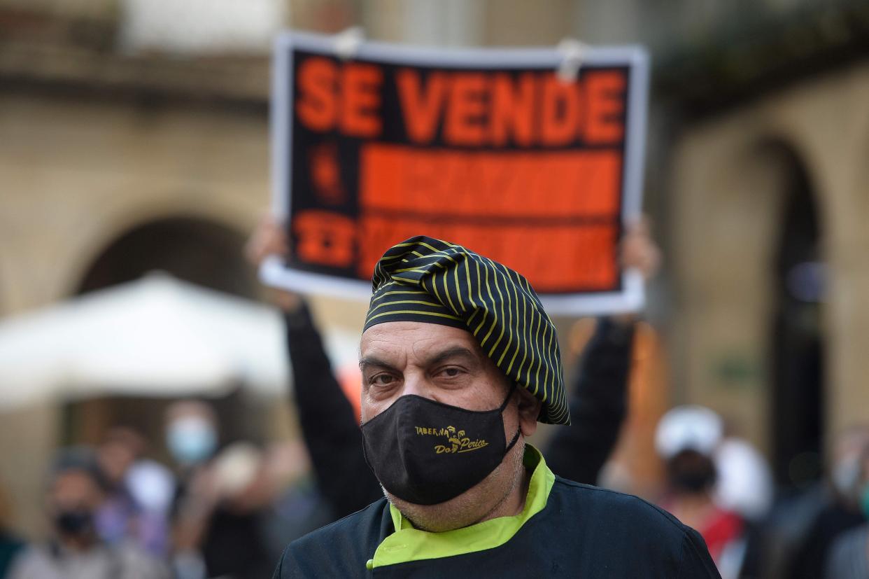 A cook stands next to a “For sale” sign during a protest in support of restaurants and bars and to demand changes in the strict time regulations amid the coronavirus pandemic in Ourense, northwestern Spain, on October 14, 2020.  (Photo by MIGUEL RIOPA/AFP via Getty Images) (AFP via Getty Images)
