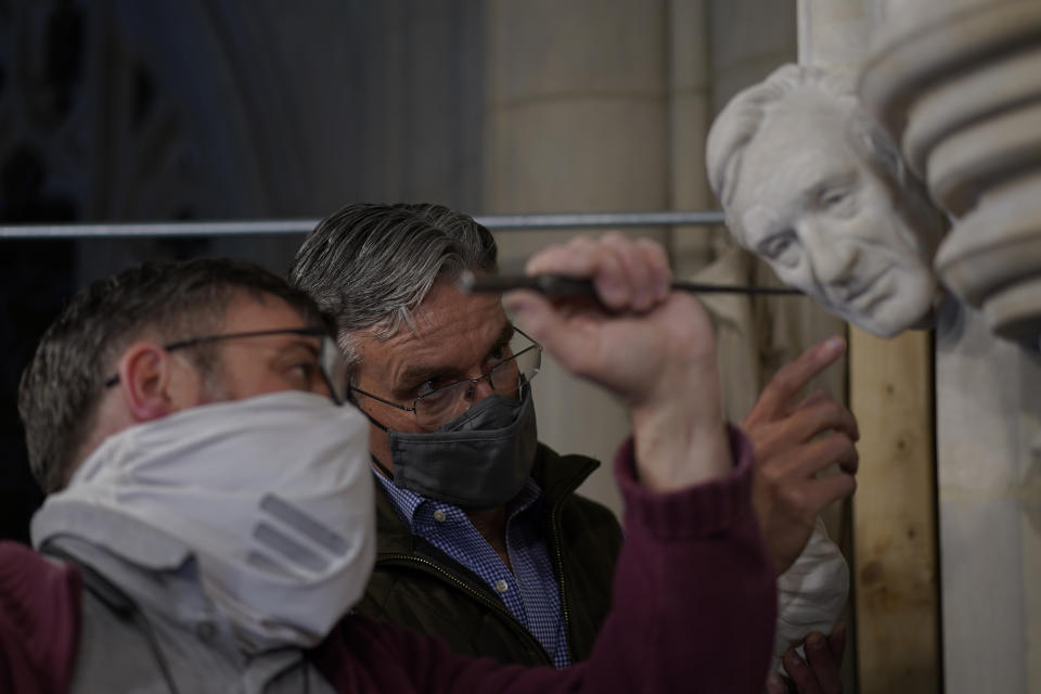 Artist Chas Fagan, right, works to fine tune his sculpture of Holocaust survivor and Nobel Peace Prize winning author Elie Wiesel with stone carver Sean Callahan in the Human Rights Porch of the Washington National Cathedral, Friday, April 16, 2021. Fagan, who created all the sculptures in the Human Rights Porch, worked off photos and videos provided by Wiesel’s family to fashion a clay sculpture of Wiesel's head that Callahan and head stonemason Joe Alonso used to make a plaster model. Then Callahan, using specialized calibration equipment, painstakingly carved the image into a small slab of rock that has been sticking out of the wall for years awaiting a fourth face. (AP Photo/Carolyn Kaster)