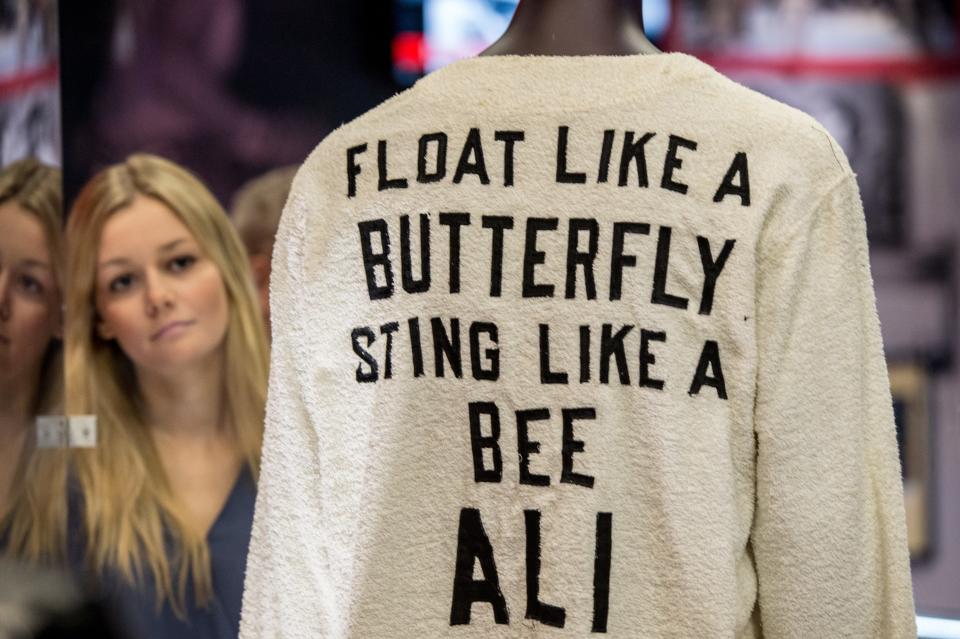 LONDON, ENGLAND - MARCH 03:  Sarah Foster, 21, looks at a signed 'Float like a butterfly sting like a bee' robe worn by Ali's cornerman Bundini Brown at the 'Rumble in the Jungle' fight - at the preview of the 'I Am The Greatest' Muhammad Ali exhibition on March 3, 2016 in London, England.  The exhibition showcases the life and career of heavyweight boxer Muhammad Ali and features over more than 100 artefacts including personal memorabilia, unseen footage and photographs. It is open to the public from Friday March 4, 2016 at the O2 in London.  (Photo by Chris Ratcliffe/Getty Images)