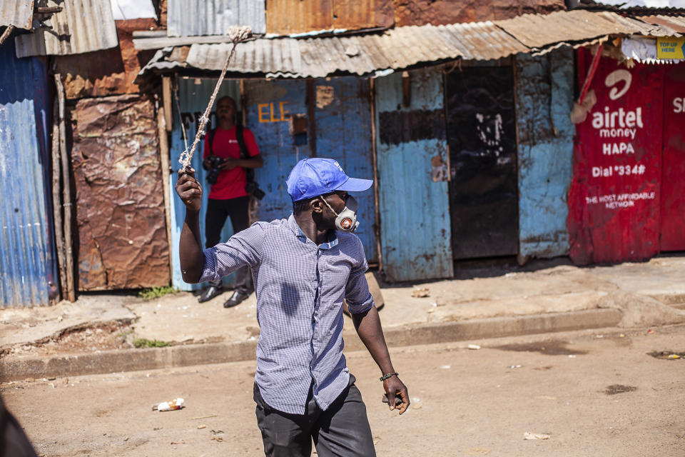 A Protester throws stones towards police officers during a mass rally called by the opposition leader Raila Odinga over the high cost of living in Kibera Slums, Nairobi, Monday, March 27, 2023. Police in Kenya are on high alert ahead of the second round of anti-government protests organized by the opposition that has been termed as illegal by the government. Police chief Japheth Koome insists that Monday's protests are illegal but the opposition leader Raila Odinga says Kenyans have a right to demonstrate. (AP Photo/Samson Otieno)