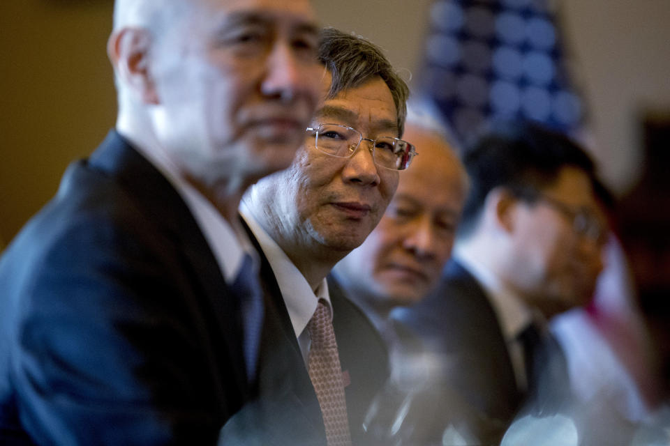 China's Central Bank Governor Yi Gang, center, accompanies Chinese Vice Premier Liu He, left, and other Chinese officials as they begin US-China Trade Talks with US Trade Representative Robert Lighthizer and other Trump Administration officials in the Diplomatic Room of the Eisenhower Executive Office Building on the White House Complex, Wednesday, Jan. 30, 2019, in Washington. (AP Photo/Andrew Harnik)