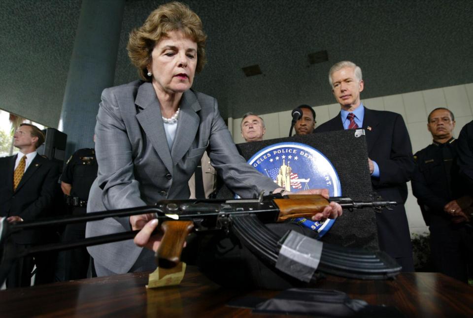 California Gov. Gray Davis (R) watches as Sen. Dianne Feinstein, D-California, picks up a Chinese-made AK-47 assault rifle