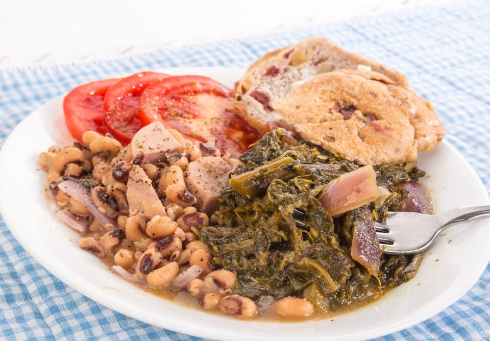 collard greens seasoned with salt pork and red onions and black eyed peas with chunks of spam blue gingham tablecloth emphasizes country kitchen feel