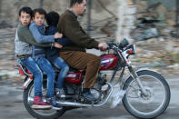 Boys ride a motorcycle with a man in rebel-held besieged old Aleppo, Syria December 2, 2016. REUTERS/Abdalrhman Ismail