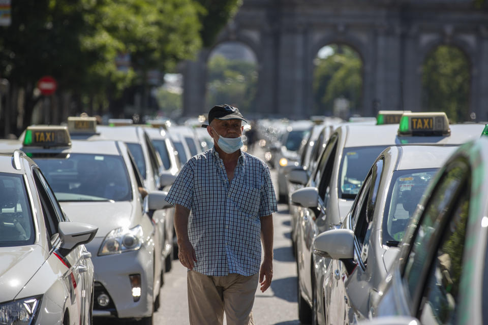 A taxi driver wearing a face mask to prevent the spread of coronavirus walks amid a taxi drivers protest in downtown Madrid, Spain, Tuesday, June 30, 2020. Taxi drivers are demanding assistance due to lack of clients and private hire. (AP Photo/Manu Fernandez)