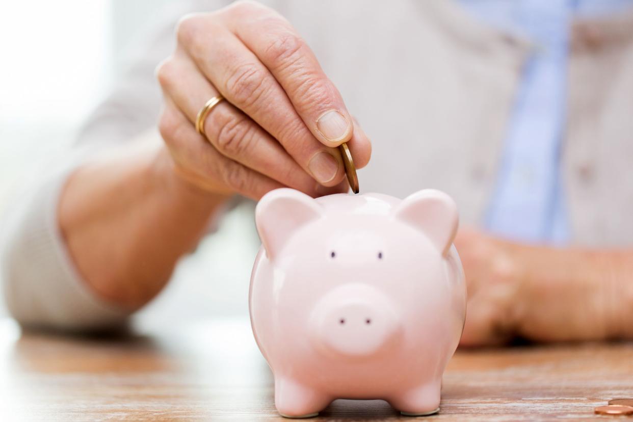 Woman's hand putting money into a piggy bank