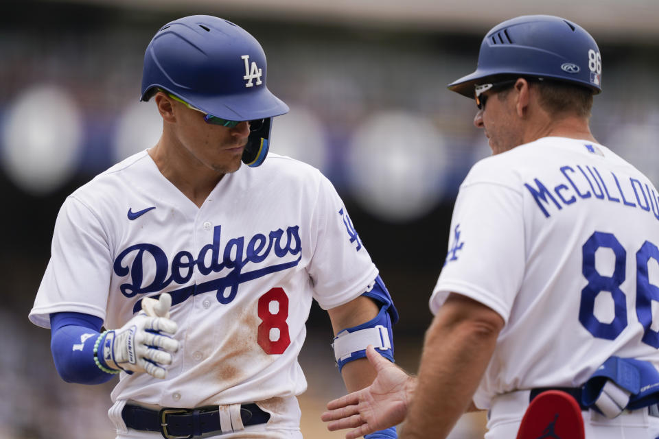 Los Angeles Dodgers' Kiké Hernández slaps hands with first base coach Clayton McCullough after hitting a single during the eighth inning in the first baseball game of a doubleheader against the Miami Marlins, Saturday, Aug. 19, 2023, in Los Angeles. (AP Photo/Ryan Sun)