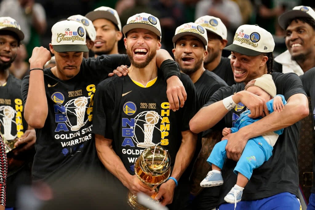 Golden State Warriors guard Stephen Curry, center, celebrates with teammates as he holds the Bill Russell Trophy for Most Valuable Player on June 16, 2022 after the Warriors beat the Boston Celtics in Game 6 to win basketball’s NBA Finals in Boston. (AP Photo/Steven Senne)