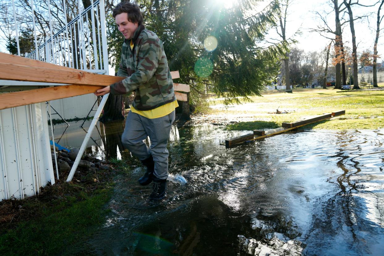 Daniel B. Atkins, 23, is shown in the flooded backyard of his Harding Avenue home, in Westwood, as he holds two pieces of lumber, Wednesday, January 10, 2024.