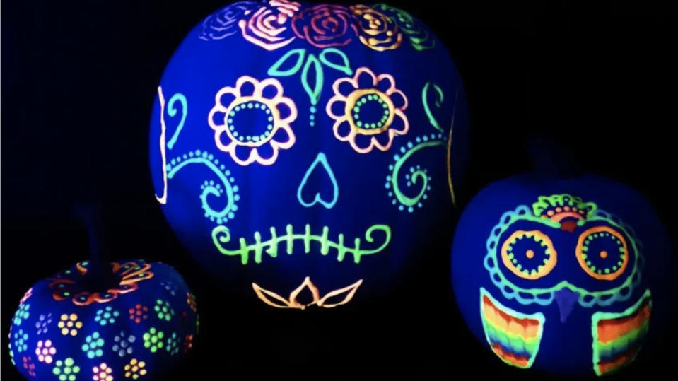 Pumpkin faces painted to look like sugar skulls using glow in the dark puffy paint