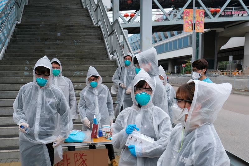 Residents wearing masks and raincoats volunteer to take temperature of passengers following the outbreak of a new coronavirus at a bus stop at Tin Shui Wai, a border town in Hong Kong