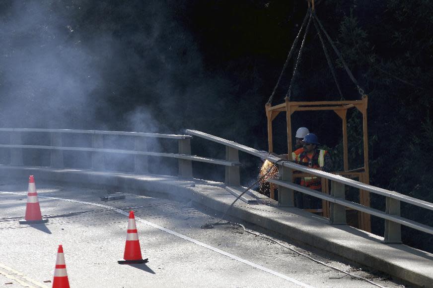 Crews work to cut away rails from the Pfeiffer Canyon Bridge on Highway 1 on Monday, March 13, 2017, in Big Sur, Calif. The bridge was compromised after slides occurred in the area associated with this winter's heavy rains. (AP Photo/Nic Coury)