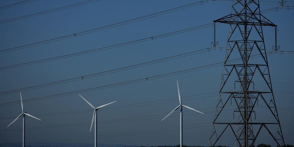 Wind turbines behind a series of electrical lines.