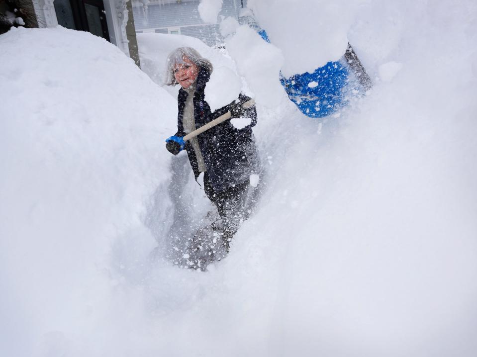 Sarah Pitt-Wooll digs through a wall of snow on her walkway after a storm left over a foot and a half  in Kittery, Maine, Sunday, Feb. 15, 2015.