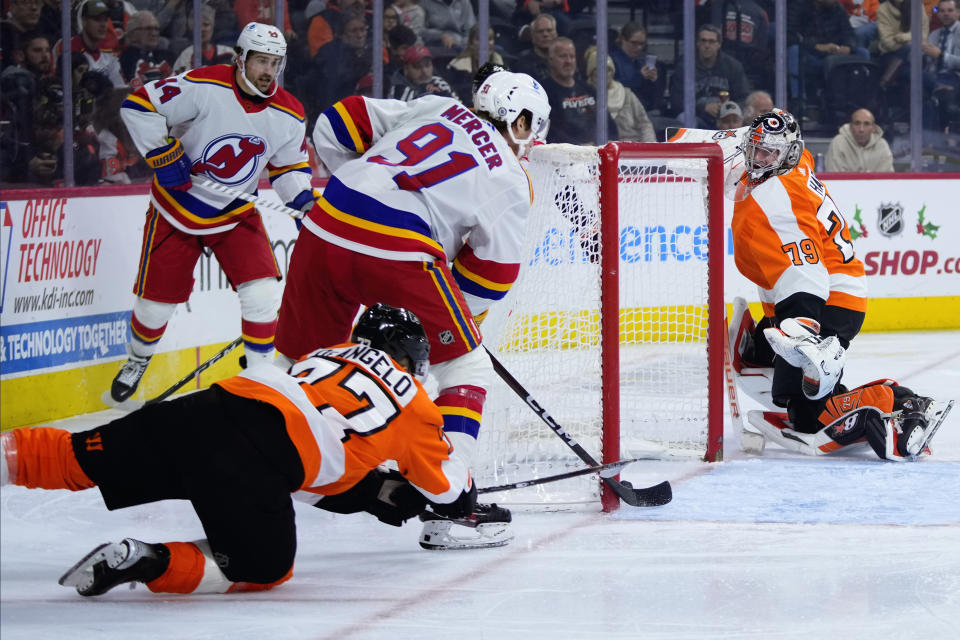 New Jersey Devils' Dawson Mercer (91) scores a goal against Philadelphia Flyers' Tony DeAngelo (77) and Carter Hart (79) during the third period of an NHL hockey game, Saturday, Dec. 3, 2022, in Philadelphia. (AP Photo/Matt Slocum)