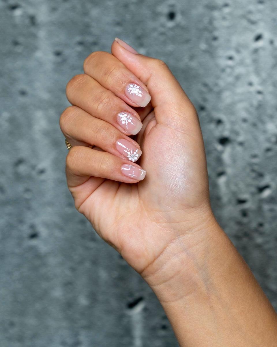 a persons hand with painted nails in a natural color with starbursts in white and silver