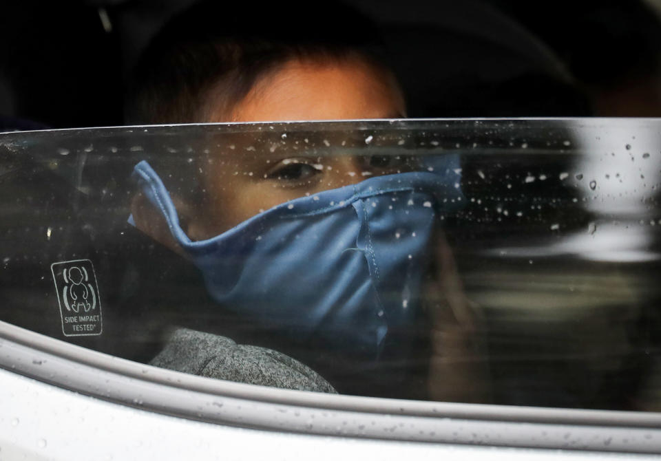 A boy wears a face mask as food is delivered to his family's truck at a food bank distribution center in Van Nuys, California, in April. At the time, organizers said they had distributed food for 1,500 families during the COVID-19 pandemic. (Photo: Mario Tama via Getty Images)