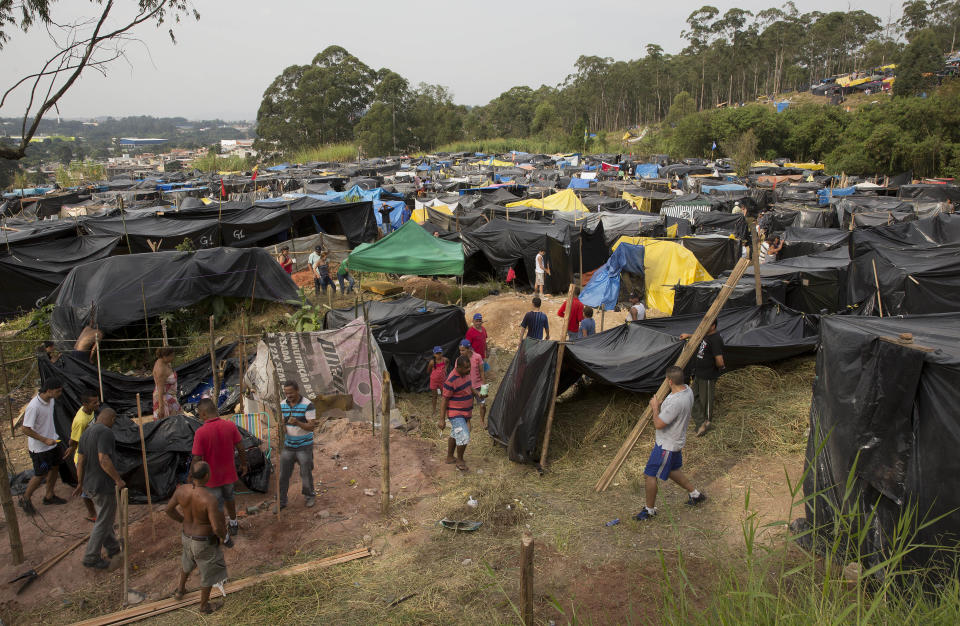 Members of the Homeless Workers Movement build their shacks on occupied land within view of Itaquerao stadium in Sao Paulo, Brazil, Tuesday, May 6, 2014. Thousands of impoverished Brazilians have squatted near the World Cup stadium hosting the opening match of soccer’s biggest tournament, saying the arena’s construction is to blame for rent increases that drove them out of their homes. (AP Photo/Andre Penner)