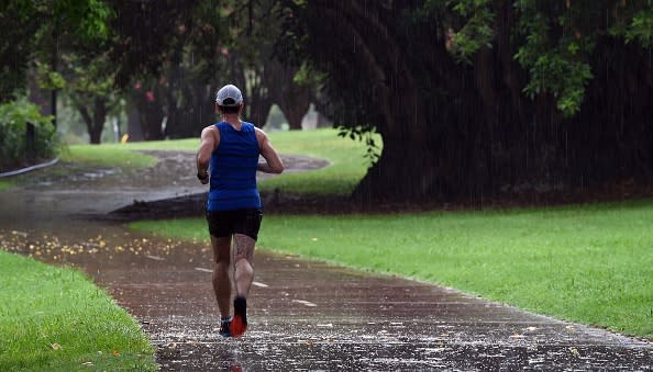 A man runs in a wet Brisbane park.