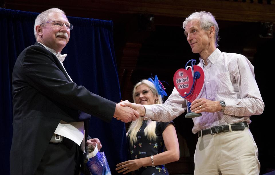 David Wartinger, left, accepts his Ig Nobel award from Nobel laureate Wolfgang Ketterle (physics, 2001) during ceremonies at Harvard University in Cambridge, Mass., Thursday, Sept. 13, 2018. Wartinger won for for using roller coaster rides to try to hasten the passage of kidney stones. (AP Photo/Michael Dwyer)