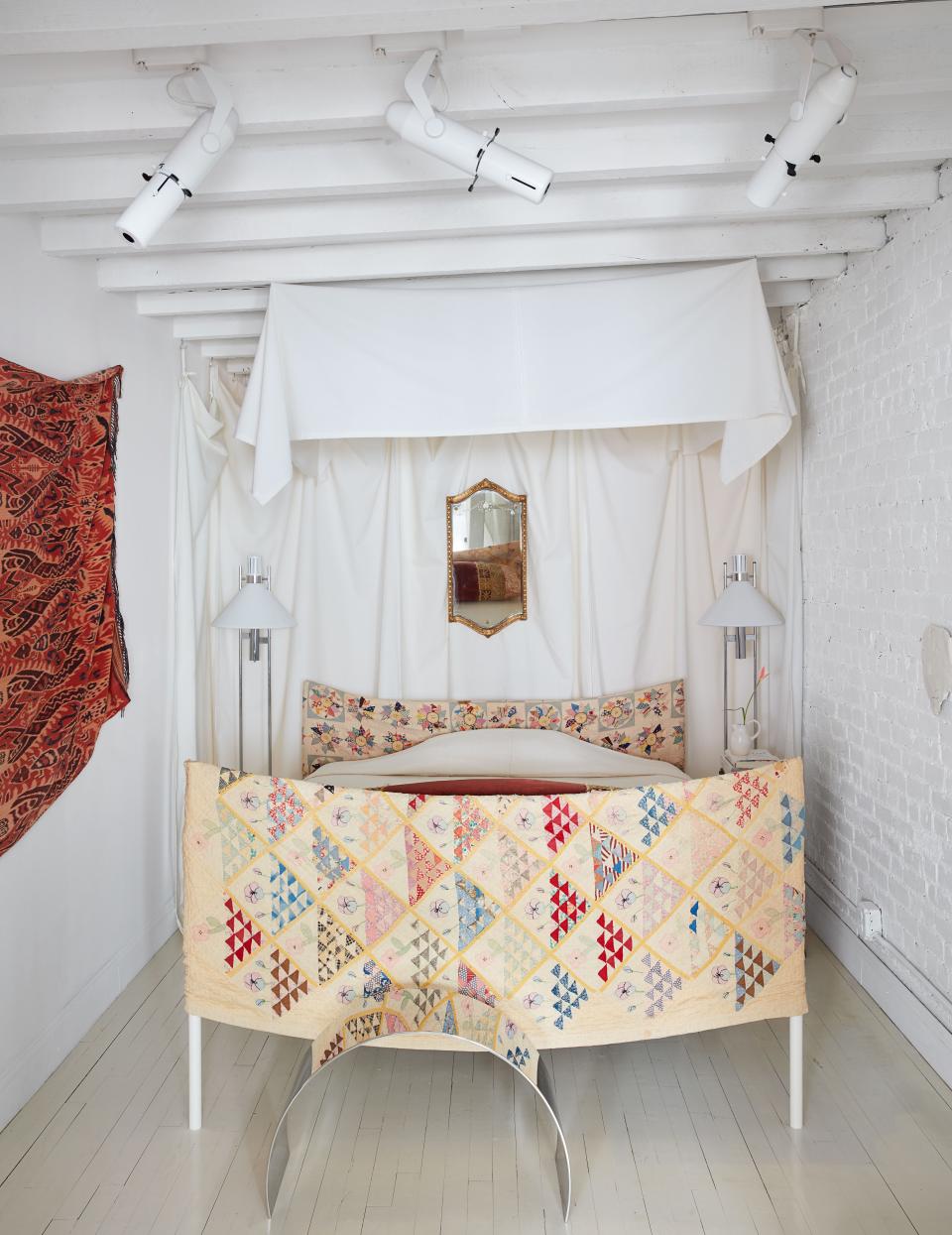 Vintage Robert Sonneman floor lamps flank the bed, which he slipcovered in a patchwork quilt.