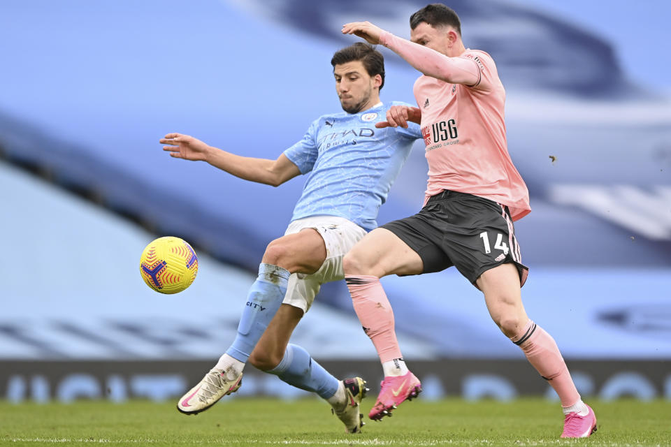 Sheffield United's Oliver Burke, right, is challenged by Manchester City's Ruben Dias during the English Premier League match between Manchester City and Sheffield United at the the City of Manchester Stadium in Manchester, England, Saturday, Jan. 30, 2021. (Laurence Griffiths/Pool via AP)