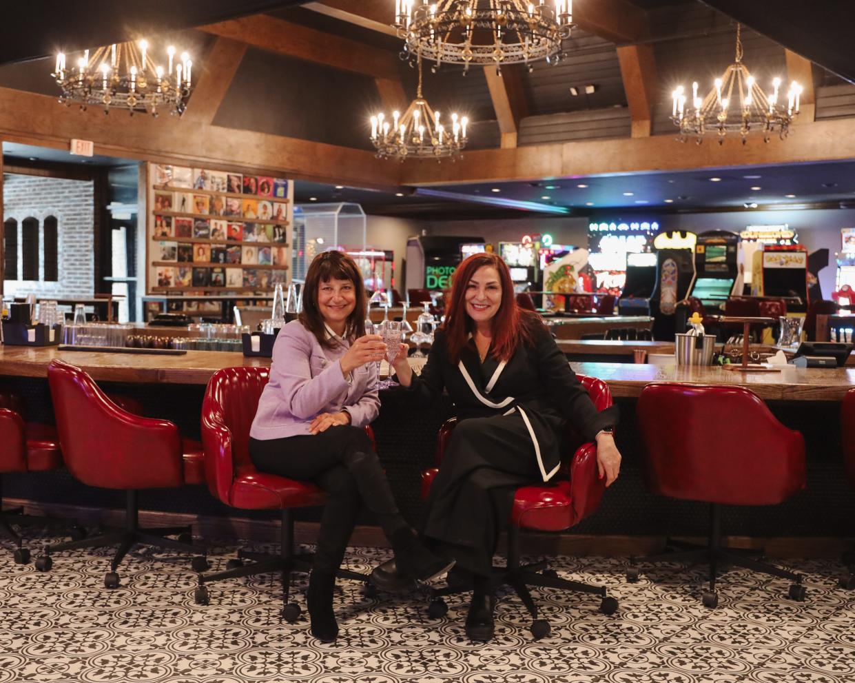 Angela Harrington, left and Danise Petsel clink glasses at the "sunken bar" inside the Supper Club of the newly-renovated Highlander Hotel in Iowa City, Iowa. Petsel's food service team is migrating from the Iowa River Power Restaurant, which closed in 2023 after a dispute between the Petsels and the building owner.