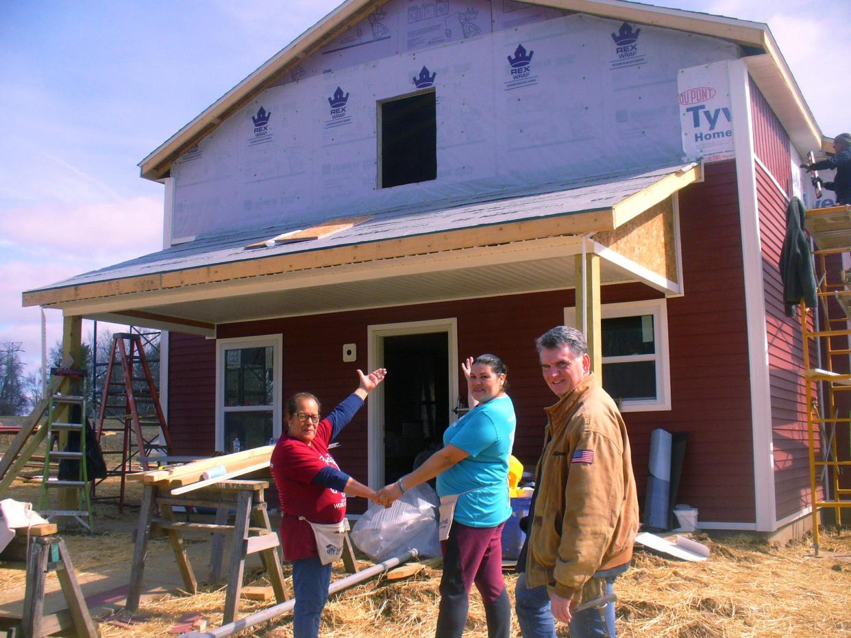 Laura Gallegos (center) and her mother, Juana Franco, the future owners, gesture toward the new Habitat for Humanity house under construction at 2015 S. Bernard Drive in Bloomington. At right is Indiana State Treasurer Daniel Elliott. Braver Angels, a volunteer national organization, recruited local politicians and candidates to help with the build.