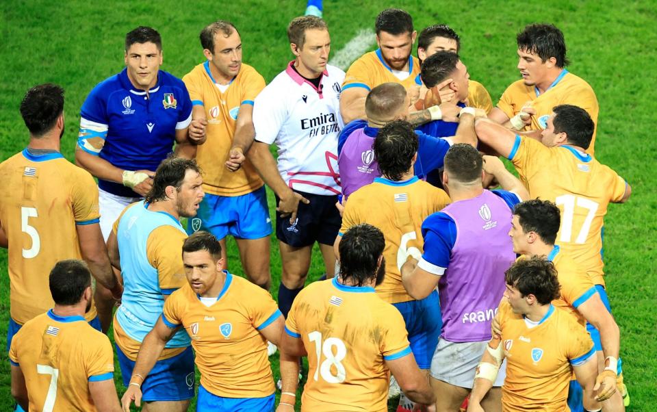Australian referee Angus Gardner (centre) watches on as Italy and Uruguay players argue