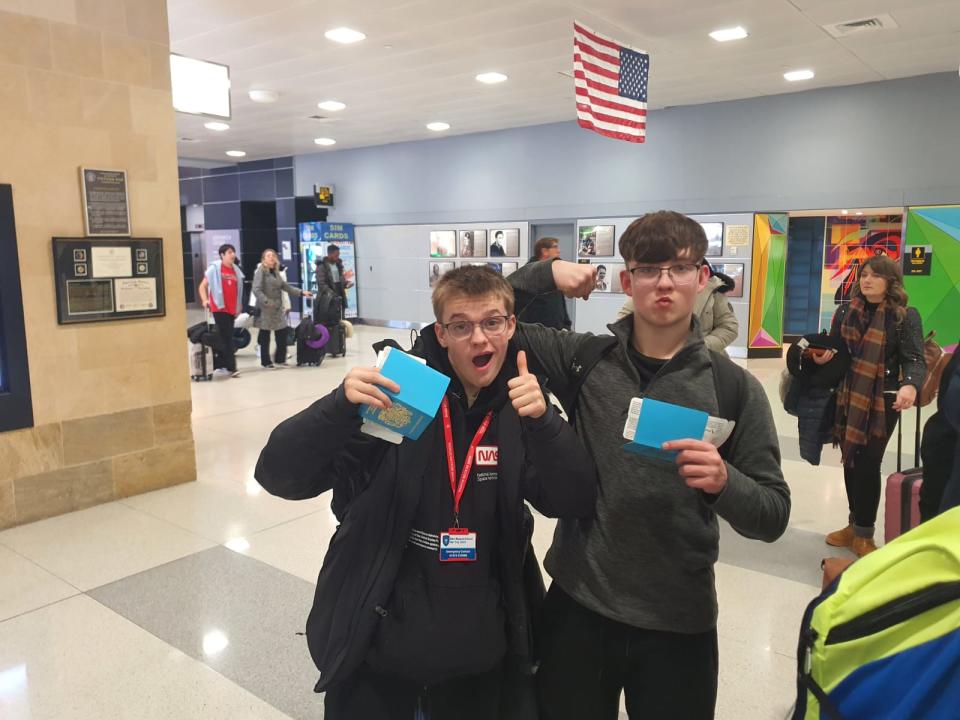 image of two students posing with passports in airport