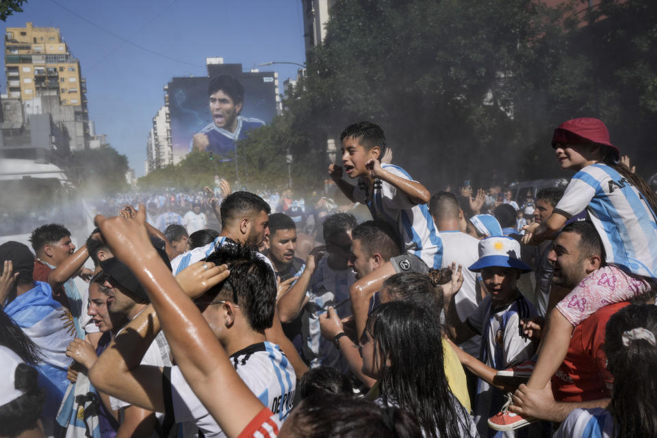 Fanáticos del fútbol que esperan para ver a la selección de fútbol de Argentina que ganó la Copa del Mundo son rociados con agua por trabajadores municipales en Buenos Aires, Argentina, el martes 20 de diciembre de 2022. (AP Foto/Rodrigo Abd)