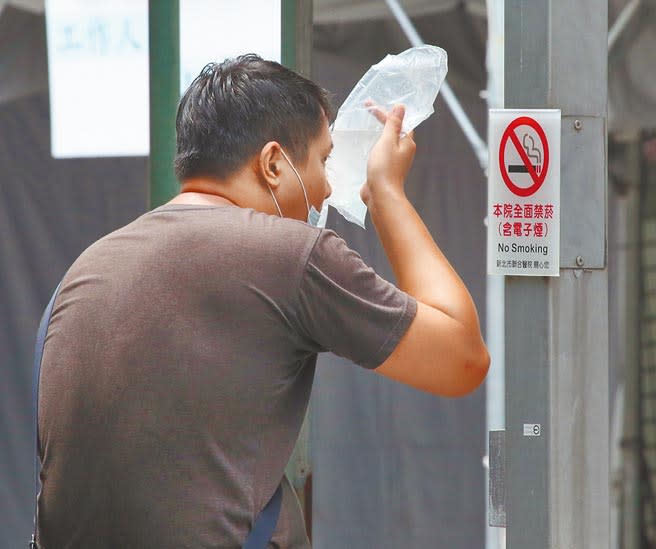 三級警戒延長到7月底，夏月電價緩徵是否跟進受到關注，朝野立委齊聲呼籲降低民眾負擔。新北市立聯合醫院三重院區快篩站11日有受檢民眾因採檢後不舒服，拿冰水袋壓在鼻子上。（陳君瑋攝）