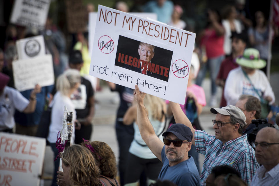 Protesters outside Trump Plaza in West Palm Beach, Fla., as President Donald Trump and first lady Melania attend the 60th annual Red Cross Ball at Trump's Mar-a-Lago resort on Saturday, Feb. 4, 2017. (Michael Ares/Palm Beach Post via AP)