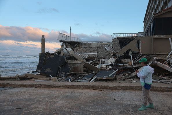 Anna Daabies stands near a condo building damaged as Hurricane Nicole came ashore on November 10, 2022, in Daytona Beach, Florida. The storm surge associated with Nicole coincided with already-high tides caused by this week's full moon, putting more stress on aging sea walls meant to protect coastal communities.