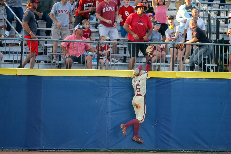 Florida Sate's Kaley Mudge (6) leaps for the ball as it goes over the fence for an Alabama home run fifth inning of a Women's College World Series softball game between Florida State and Alabama at USA Softball Hall of Fame Stadium in Oklahoma City, Monday, June 7, 2021.