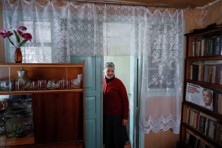 Retired school principal Nadiya Yurchenko, 79, stands in her house near a 2015 calendar featuring opposition politician Yulia Tymoshenko in the village of Skryhalivka, Kiev region, Ukraine February 11, 2019. REUTERS/Gleb Garanich