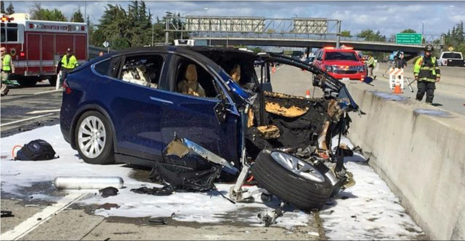 FILE - In this March 23, 2018, file photo provided by KTVU, emergency personnel work a the scene where a Tesla electric SUV crashed into a barrier on U.S. Highway 101 in Mountain View, Calif. The Apple engineer who died when his Tesla Model X crashed into the concrete barrier complained before his death that the SUV’s Autopilot system would malfunction in the area where the crash happened. The complaints were detailed in a trove of documents released Tuesday, Feb. 11, 2020, by the U.S. National Transportation Safety Board, which is investigating the March, 2018 crash that killed engineer Walter Huang.  (KTVU-TV via AP, File)