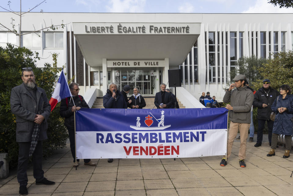 Pierre Cassen, center, a far-right activist, speaks to people gathered outside the city hall in Saint-Jean-de-Monts, western France on Saturday Nov. 4, 2023. The small movement known as the Vendee Rally, calls for farmers and fishermen to protest immigrants and foreign imports. (AP Photo/Jeremias Gonzalez)