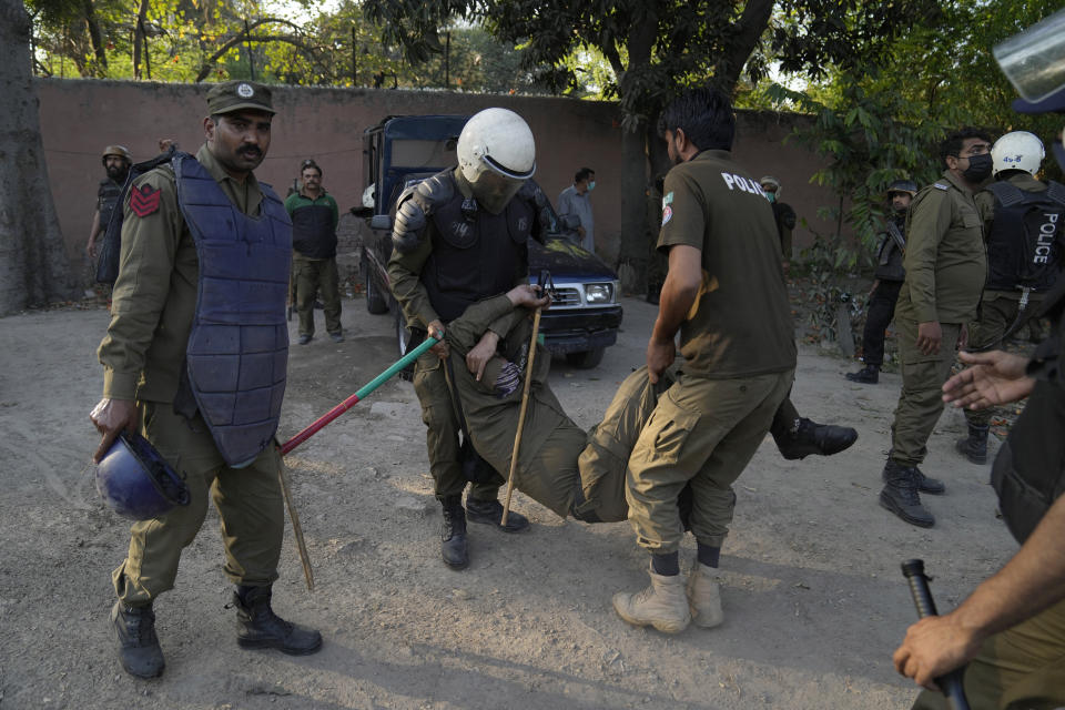 Police officers help their colleague injured in the clashes with the supporters of Pakistan's former Prime Minister Imran Khan, in Lahore, Pakistan, Wednesday, March 8, 2023. Pakistani police used water cannons and fired tear gas to disperse supporters of the country's former Prime Minister Khan Wednesday in the eastern city of Lahore. Two dozen Khan supporters were arrested for defying a government ban on holding rallies, police said. (AP Photo/K.M. Chaudary)