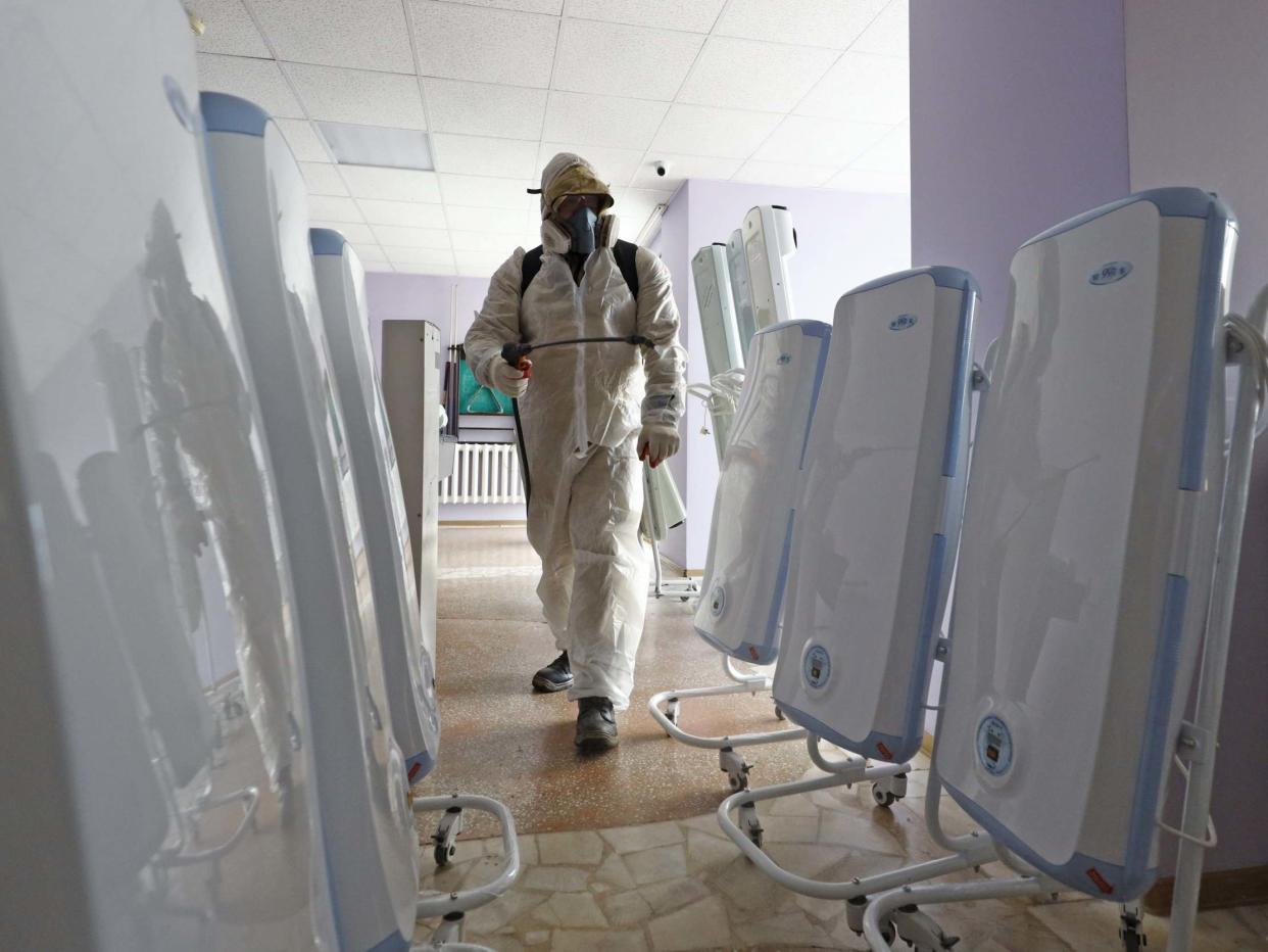 A worker in a chemical suit sprays disinfectant in a quarantine facility at the Gradostroitel health resort near the city of Tyumen after a 14-day quarantine for Russian nationals who were evacuated from Wuhan: Maxim Slutsky/TASS