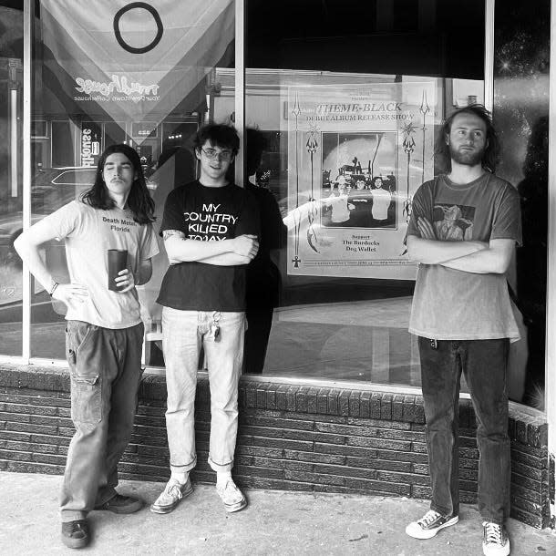 The three band members of Theme-Black pose for a photo outside of the Odyssey Lounge.