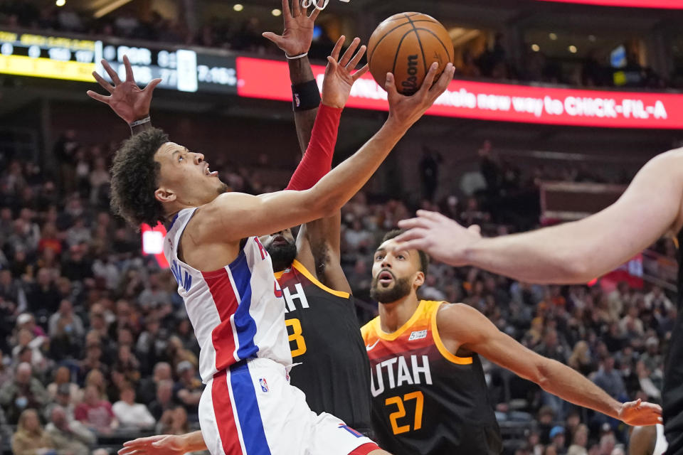 CORRECTS PISTONS PLAYER TO CADE CUNNINGHAM, INSTEAD OF CASSIUS STANLEY - Detroit Pistons guard Cade Cunningham (2) drives to the basket as Utah Jazz's Royce O'Neale, center, and Rudy Gobert (27) defend during the first half during an NBA basketball game Friday, Jan. 21, 2022, in Salt Lake City. (AP Photo/Rick Bowmer)