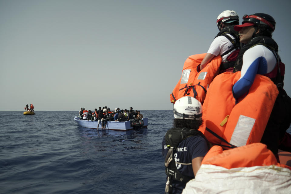 SOS Mediterranee rescuers hold life jackets as migrants on an overcrowded wooden boat wait to be saved some 53 nautical miles (98 kilometers) from the coast of Libya in the Mediterranean Sea, Tuesday, Sept. 17, 2019. The humanitarian rescue ship Ocean Viking pulled 48 people from the small boat including a newborn and a pregnant woman. (AP Photo/Renata Brito)