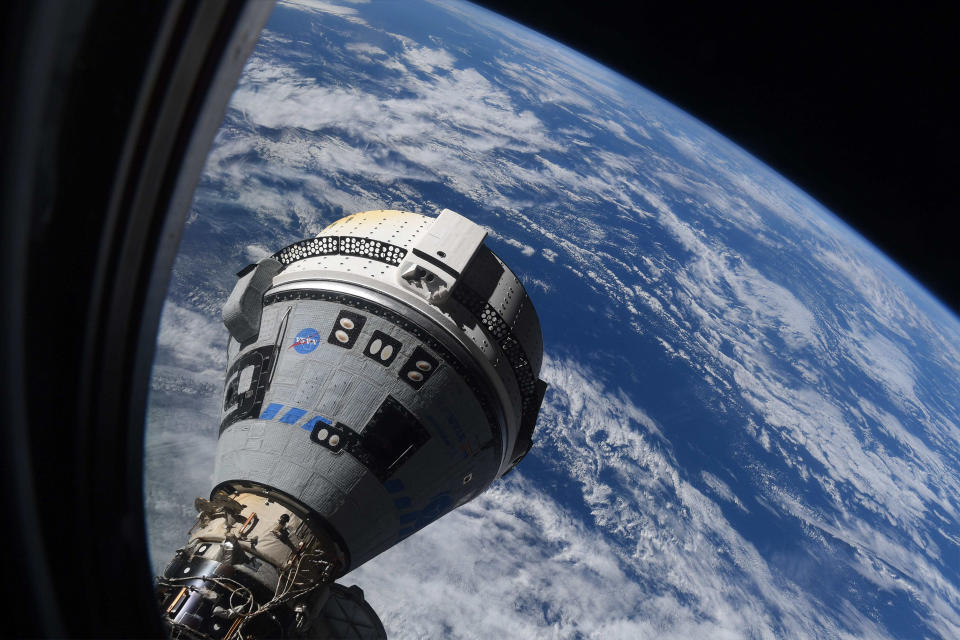 a cone-shaped spaceship visible through the window of a space station. The Earth is visible below, and the darkness of space beyond