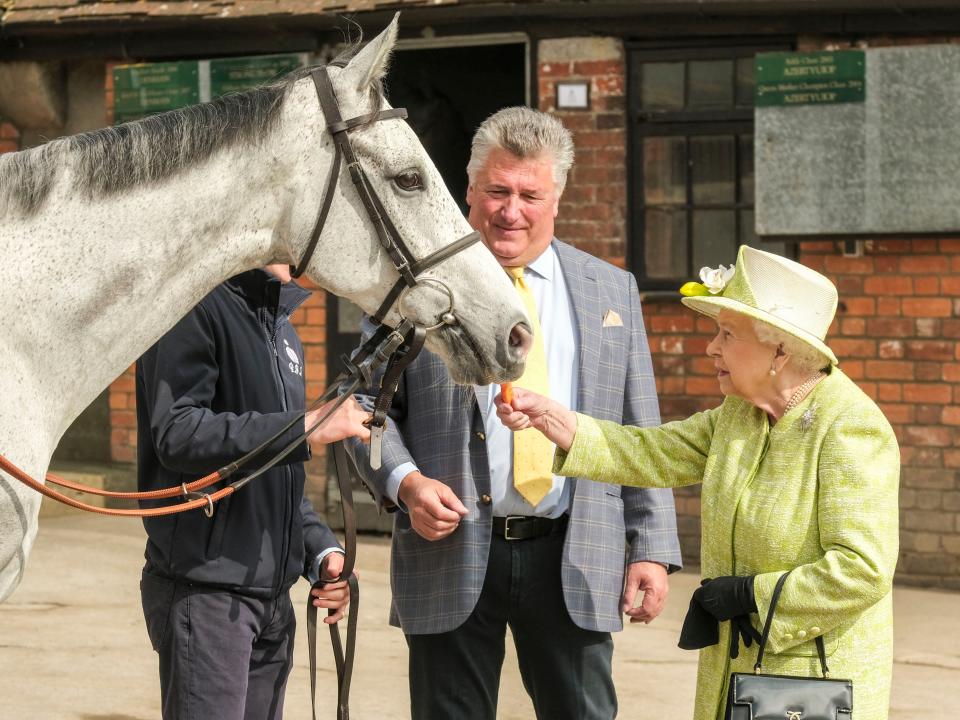 Queen Elizabeth feeding a horse a carrot.