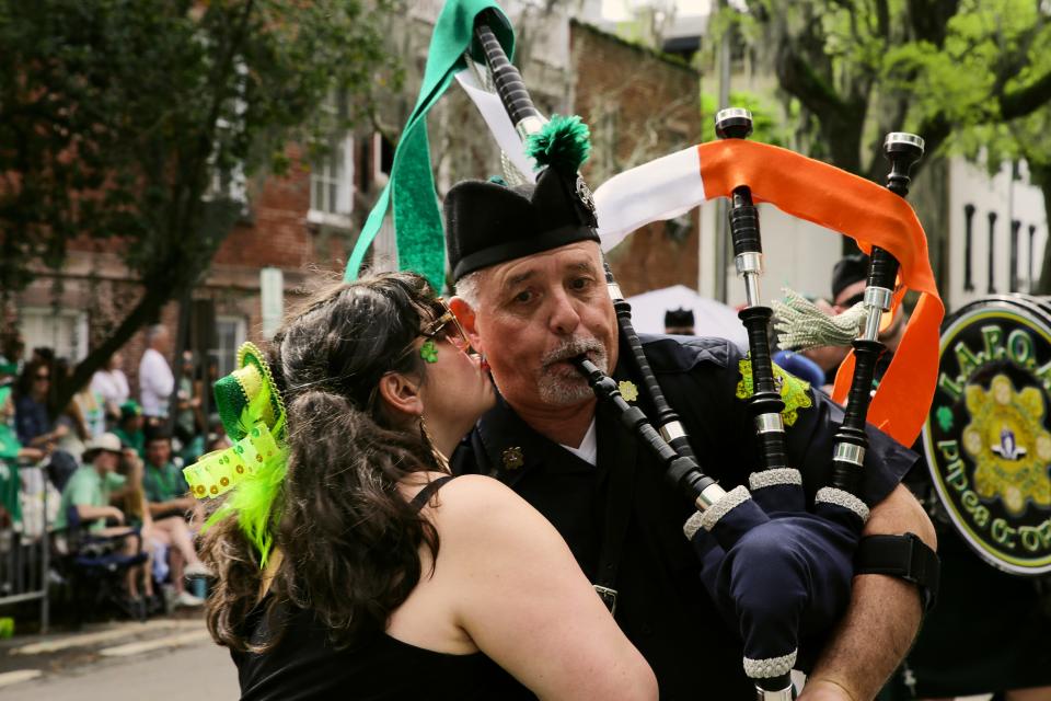 A parade goer plants a smooch on the cheek of a bagpiper from the LA Police Emerald Society during the Savannah St. Patrick's Day Parade on Saturday, March 16, 2024.
